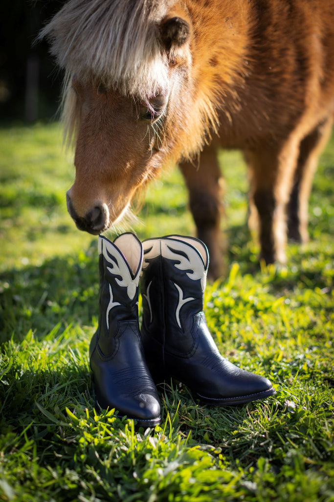 Horse standing next to cowboy boots on grass