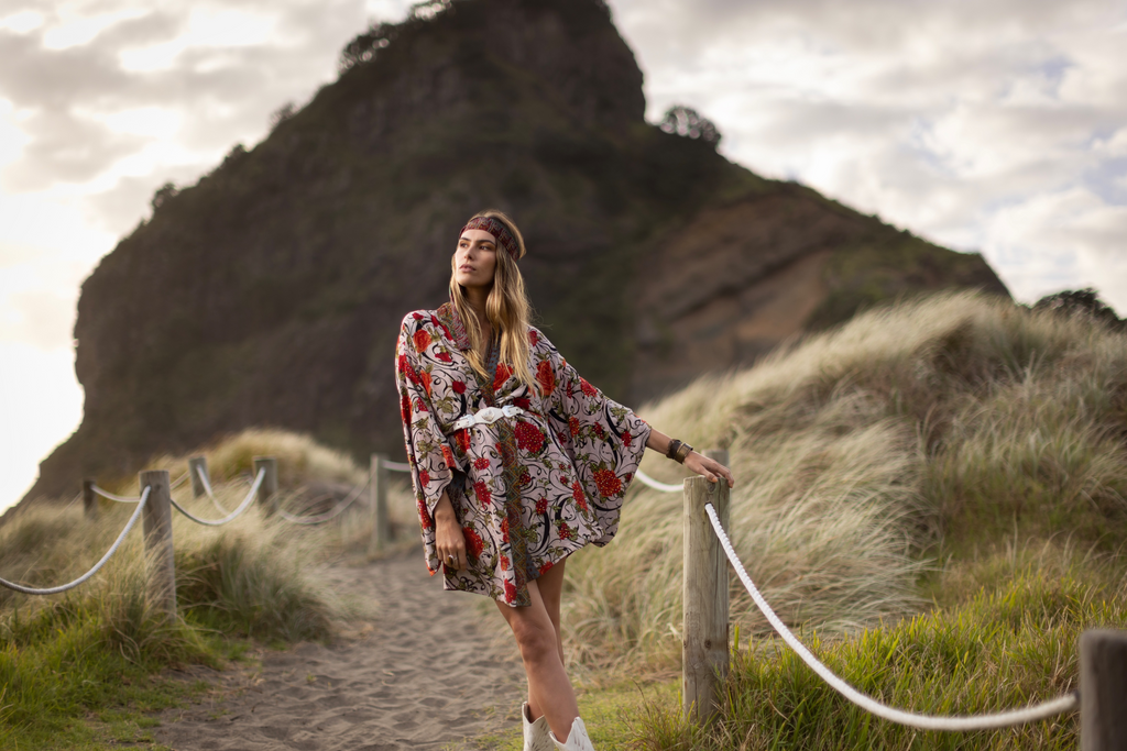 girl in vintage bohemian kimono on sandy path near rock