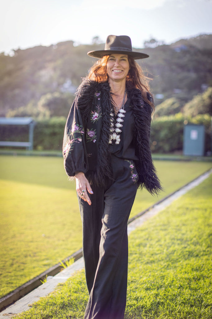 Model wearing black embroidered vest with flared trousers and cowboy boots – outdoor shoot