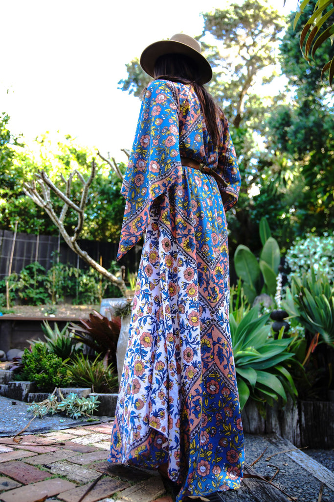 Back view of a woman wearing the Wildflower Kaftan, showcasing the flowing boho silhouette and mixed floral panels