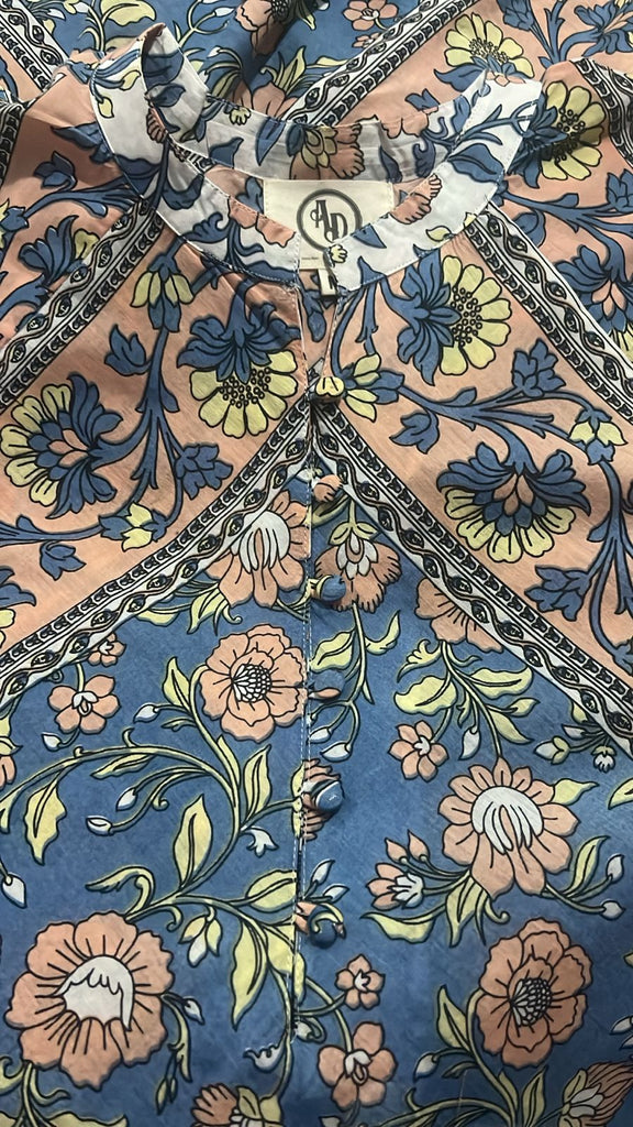 Close-up image of the Wildflower Kaftan’s covered buttons, neckline, and botanical print in blue, peach and soft yellow tones