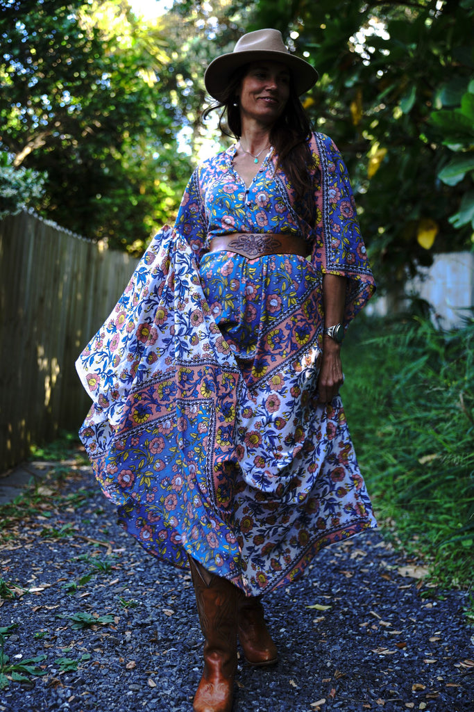 Woman walking outdoors wearing the Wildflower Kaftan with cowboy boots, showing the flowing silhouette and bohemian styling.