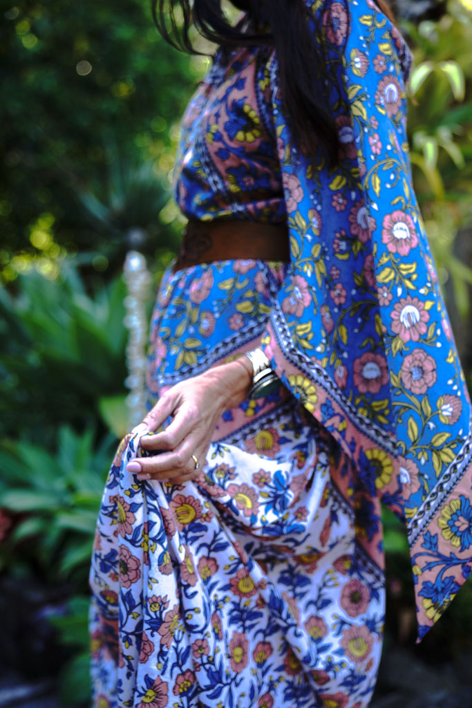 Close-up of the Wildflower Kaftan fabric as the model holds the skirt, showing the organic cotton texture and floral print details.